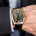 Close-up of a person wearing a gold and black wristwatch with a blurred background